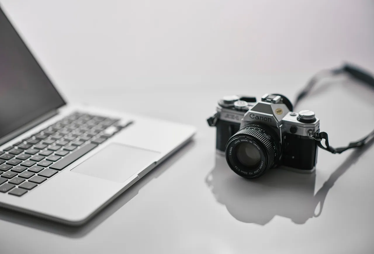 A laptop and a film camera on a white desk